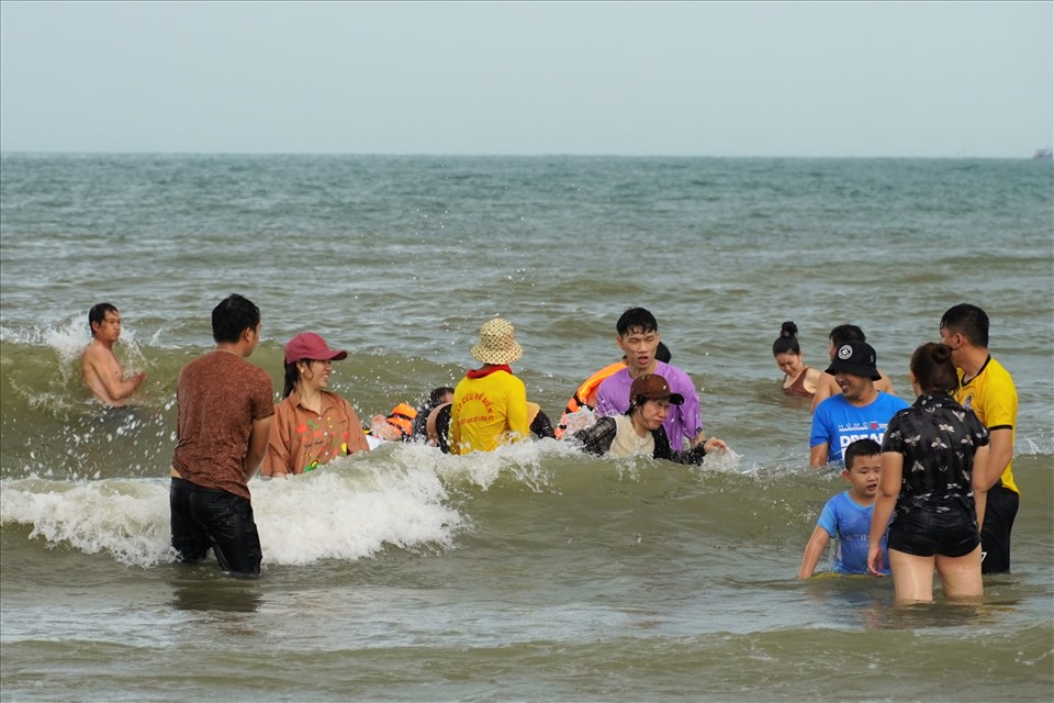 Nhiều du khách vẫn vui vẻ tắm biển và đùa vui cùng ngọn sóng, dưới sự giám sát, hướng dẫn của lực lượng cứu hộ ứng trực. Ảnh: T.A