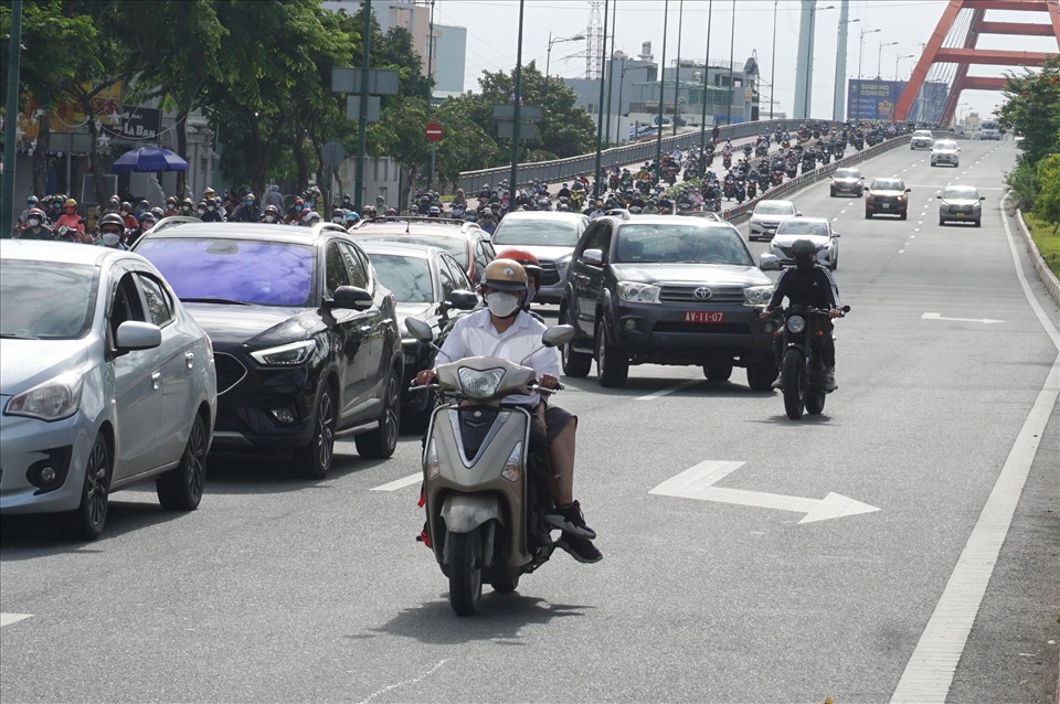 Nhiều người lái xe máy chạy sát làn đường trong cùng của ôtô, bên dải phân cách đoạn dốc cầu Bình Lợi.