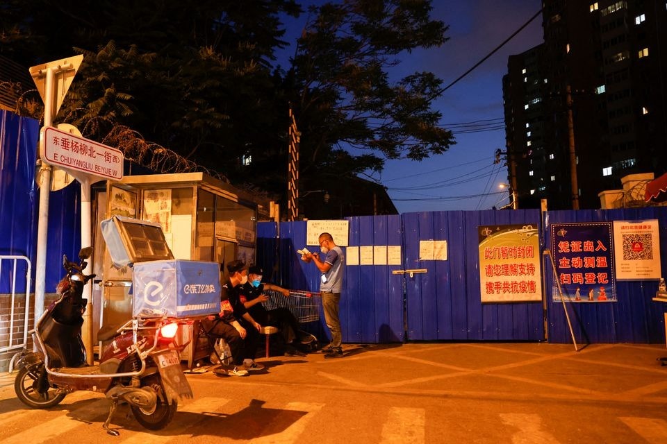 Nhân viên giao hàng chờ tại điểm kiểm soát trước một khu dân cư bị phong tỏa   ở Bắc Kinh ngày 24.5. Ảnh: Reuters