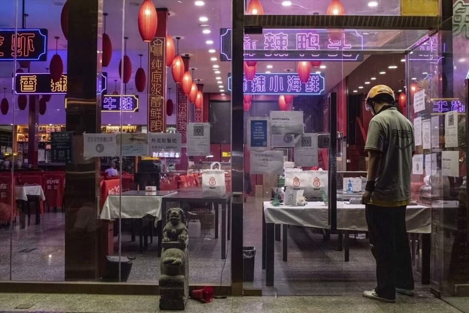 Một nhân viên giao hàng chờ lấy đồ ăn tại một nhà hàng chỉ cung cấp dịch vụ mang đi do hạn chế của Covid-19 ở Bắc Kinh. Ảnh: Bloomberg