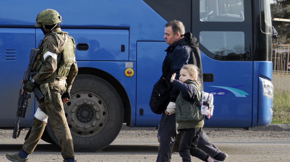 Binh sĩ Nga hộ tống một người đàn ông và một cô bé rời nhà máy Azovstal lên xe buýt ở Mariupol, ngày 6.5.2022. Ảnh: AP