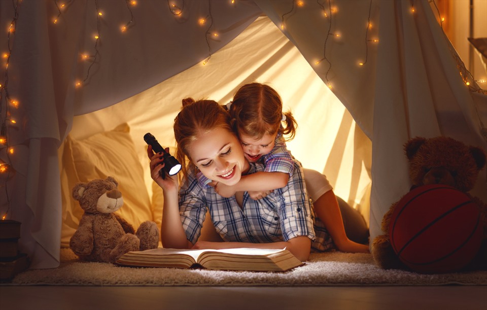 Đọc truyện nghe trước khi ngủ là hình thức tương tác rất tốt để tăng cường gắn kết giữa cha mẹ và trẻ. Ảnh: Xinhua
