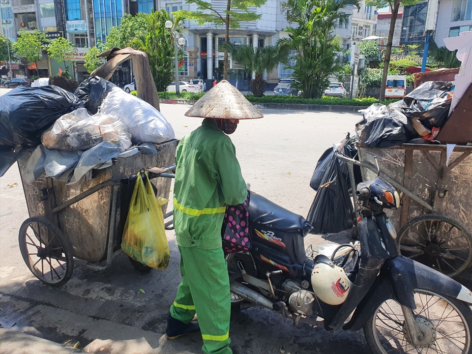 Thời tiết nắng nóng, công nhân phải sử dụng cả xe máy để kéo xe chứa rác.