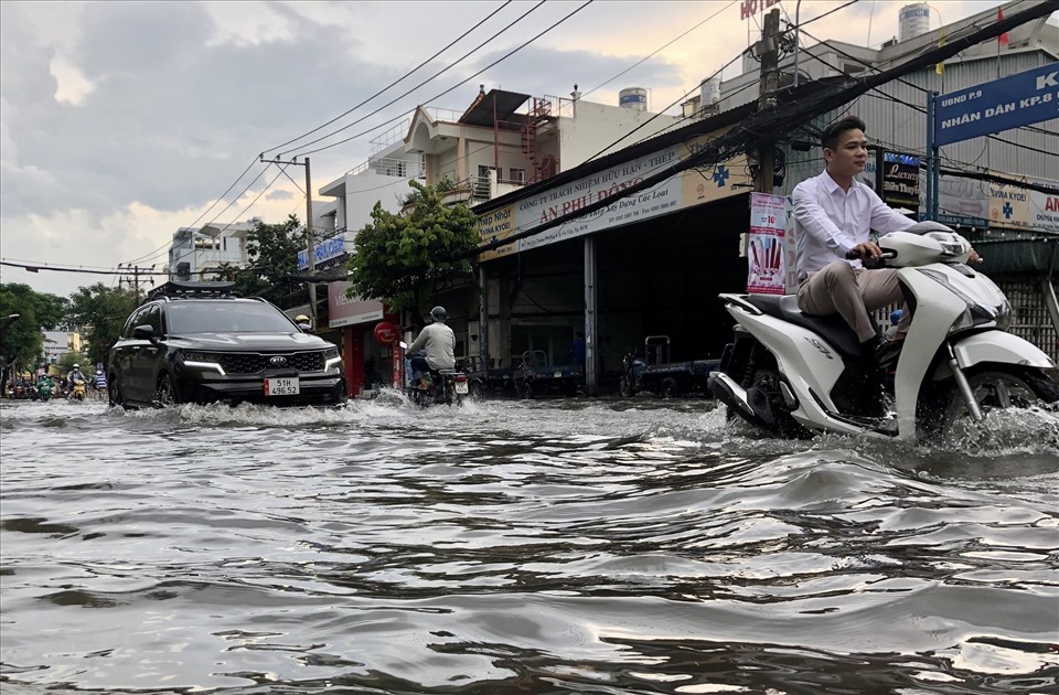 Người dân bì bõm trên đường Phạm Văn Chiêu sau cơn mưa lớn chiều 23.6