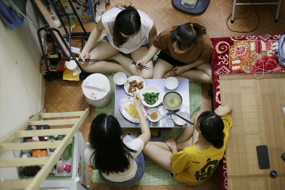 4 bạn sinh viên ngồi ăn chung bữa tối trong căn phòng trọ nhỏ, chật hẹp, oi bức