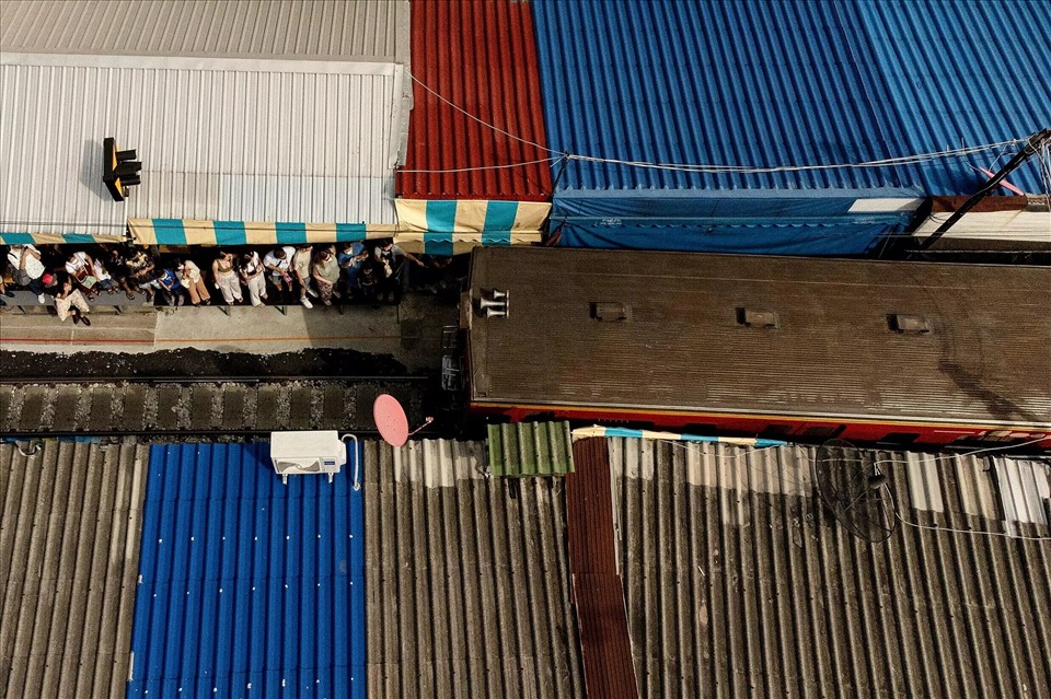 Local customers and foreign tourists have to scramble to hide in the nooks and crannies while the shopkeeper calmly moves their carts off the tracks, collapsing umbrellas to make way.