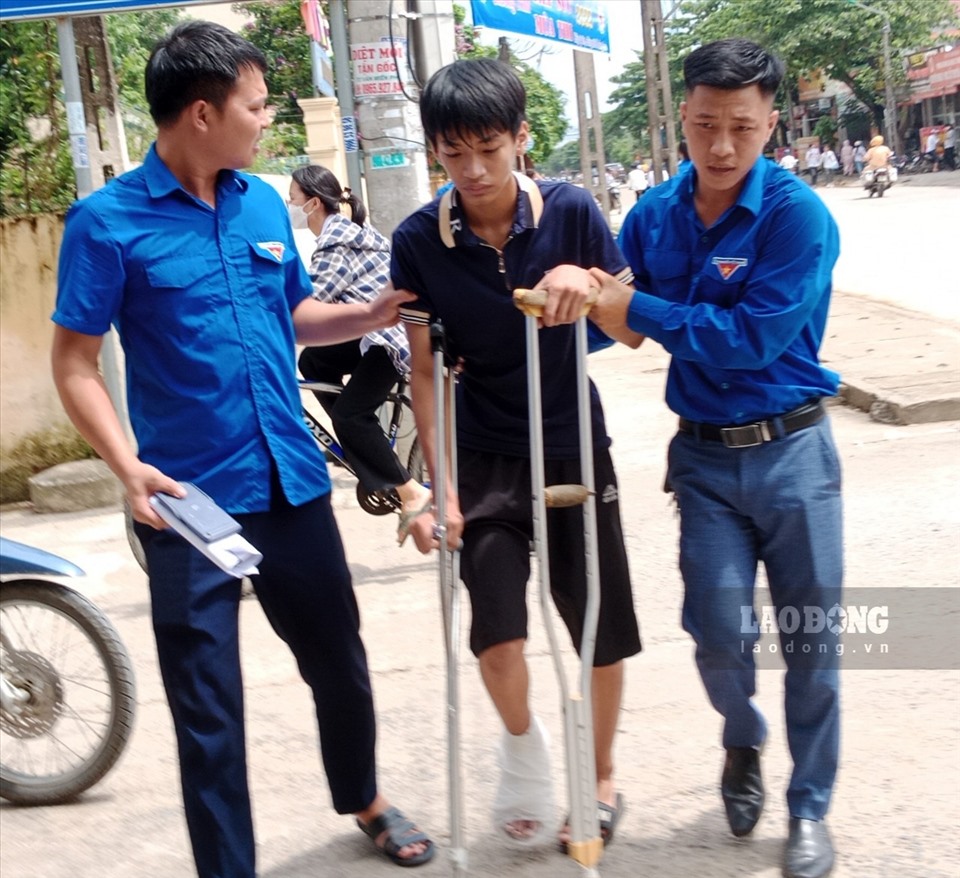 Những thí sinh bị tai nạn chấn thương ở chân, phải sử dụng nạng được các tình nguyện viên dìu đến điểm thi. Ảnh: NT