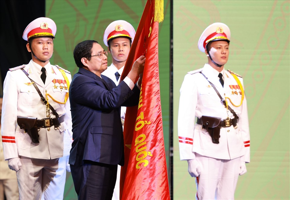 Thủ tướng Phạm Minh Chính gắn Huân chương Hồ Chí Minh lên lá cờ truyền thống của lực lượng Cảnh sát nhân dân. Ảnh: Hải Nguyễn