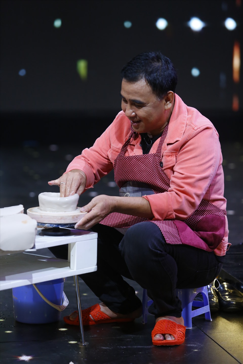 Nghệ sĩ Quyền Linh đi dép tổ ong, đeo tạp dề và ngồi ghế nhựa hào hứng tham gia thử thách của chương trình. Ảnh: VTV