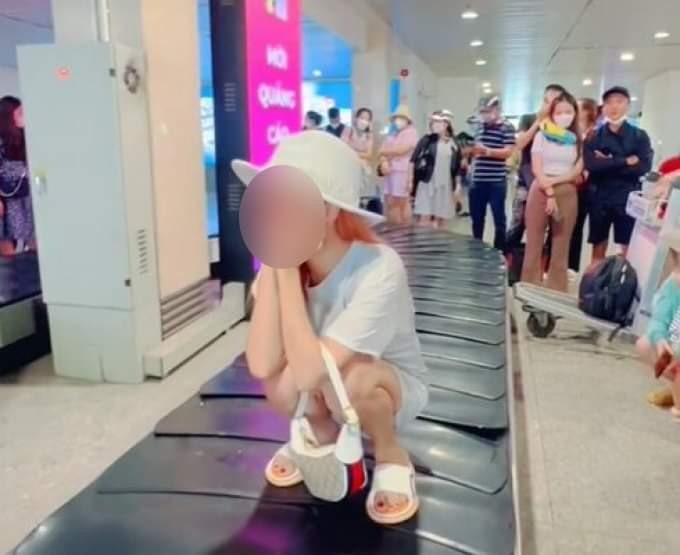 Cô gái tạo dáng trên băng chuyền hành lý sân bay.
