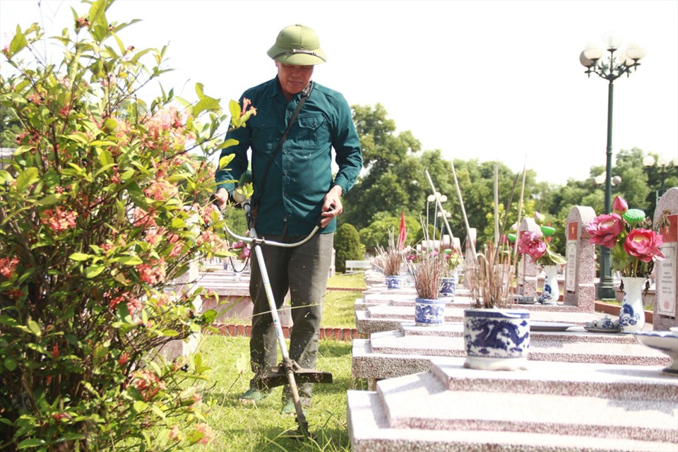 Công việc cắt tỉa cỏ trong nghĩa trang của anh Minh. Ảnh: TT.