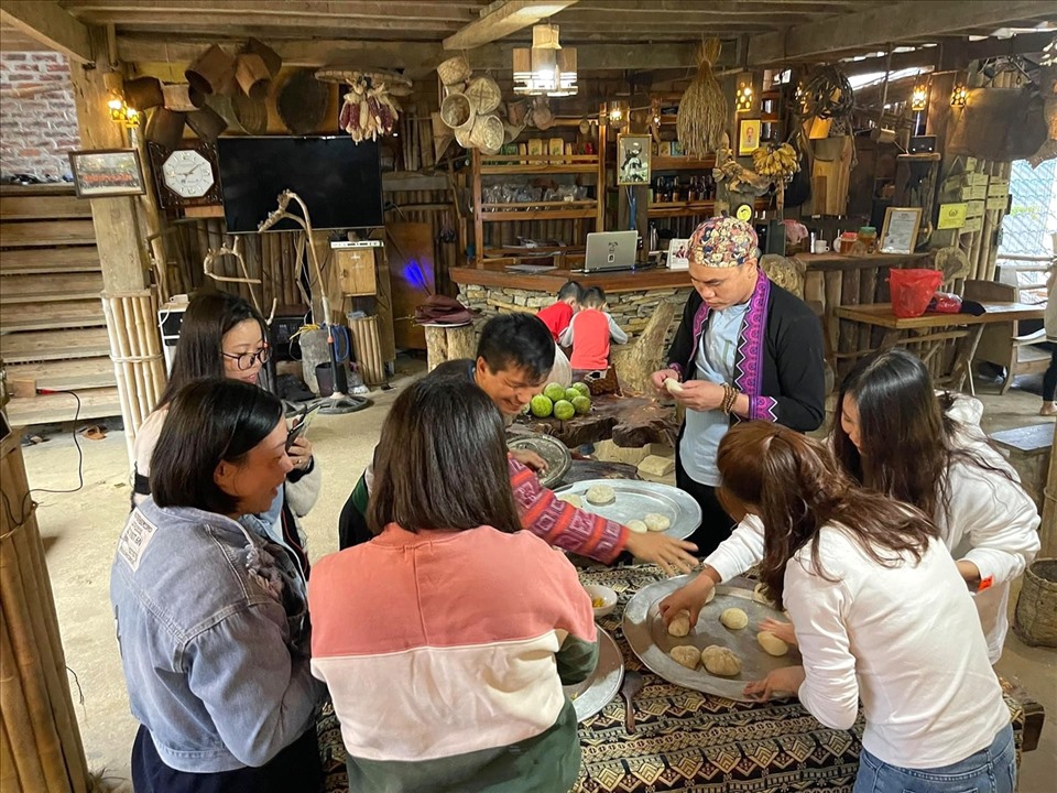 Anh Tráng A Chu cùng khách du lịch trải nghiệm cách làm bánh giày của người Mông. Ảnh: Kim Anh