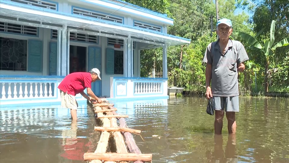 Nước ngập sân, gia đình ông Trần Công Định (huyện Phước Long) phải bắt cầu gỗ đi tạm từ lộ vào nhà