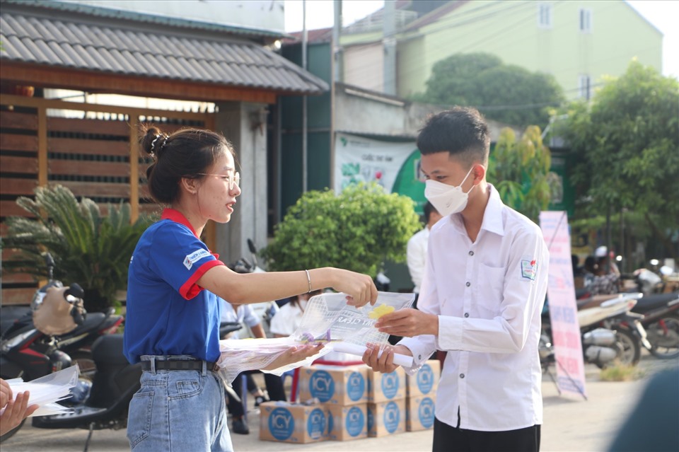 Thanh niên tình nguyện phát túi đựng đề thi, bút chì và nước cho thí sinh. Ảnh: Minh Khuê