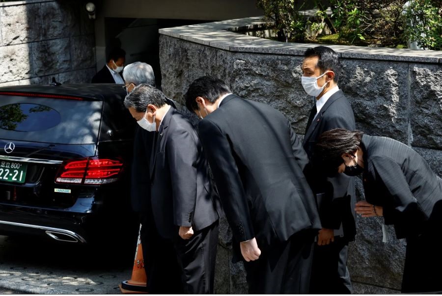 Các quan chức cúi đầu chào khi xe tang đưa thi thể ông Abe Shinzo đi vào nhà của ông ở Tokyo ngày 9.7. Ảnh chụp màn hình
