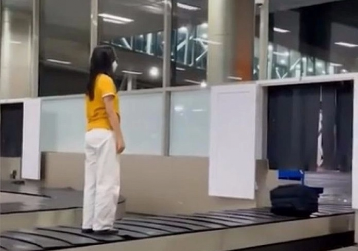 Hình ảnh nữ hành khách leo lên băng chuyền sân bay. Ảnh chụp màn hình.