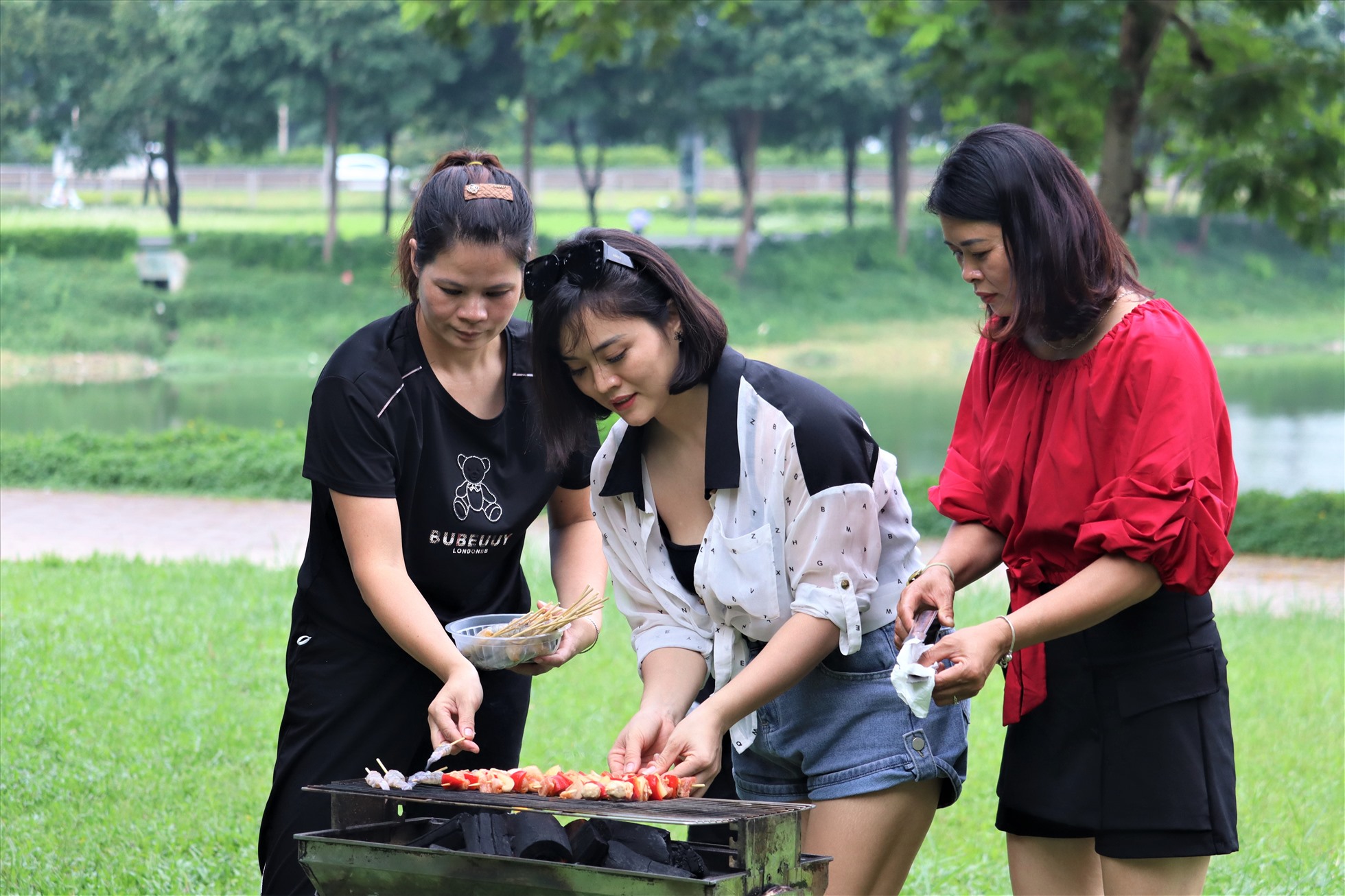 Chị Nguyễn Thị Phương Hoa (người ở giữa, Thanh Trì, Hà Nội) cùng nhóm bạn nướng thịt để chuẩn bị cho buổi tiệc nhỏ ở công viên. Chị Hoa cho biết, chi phí thuê bếp nướng (bao gồm than hoa) là 300.000 đồng, còn đồ nướng đã được ướp sẵn ở nhà.