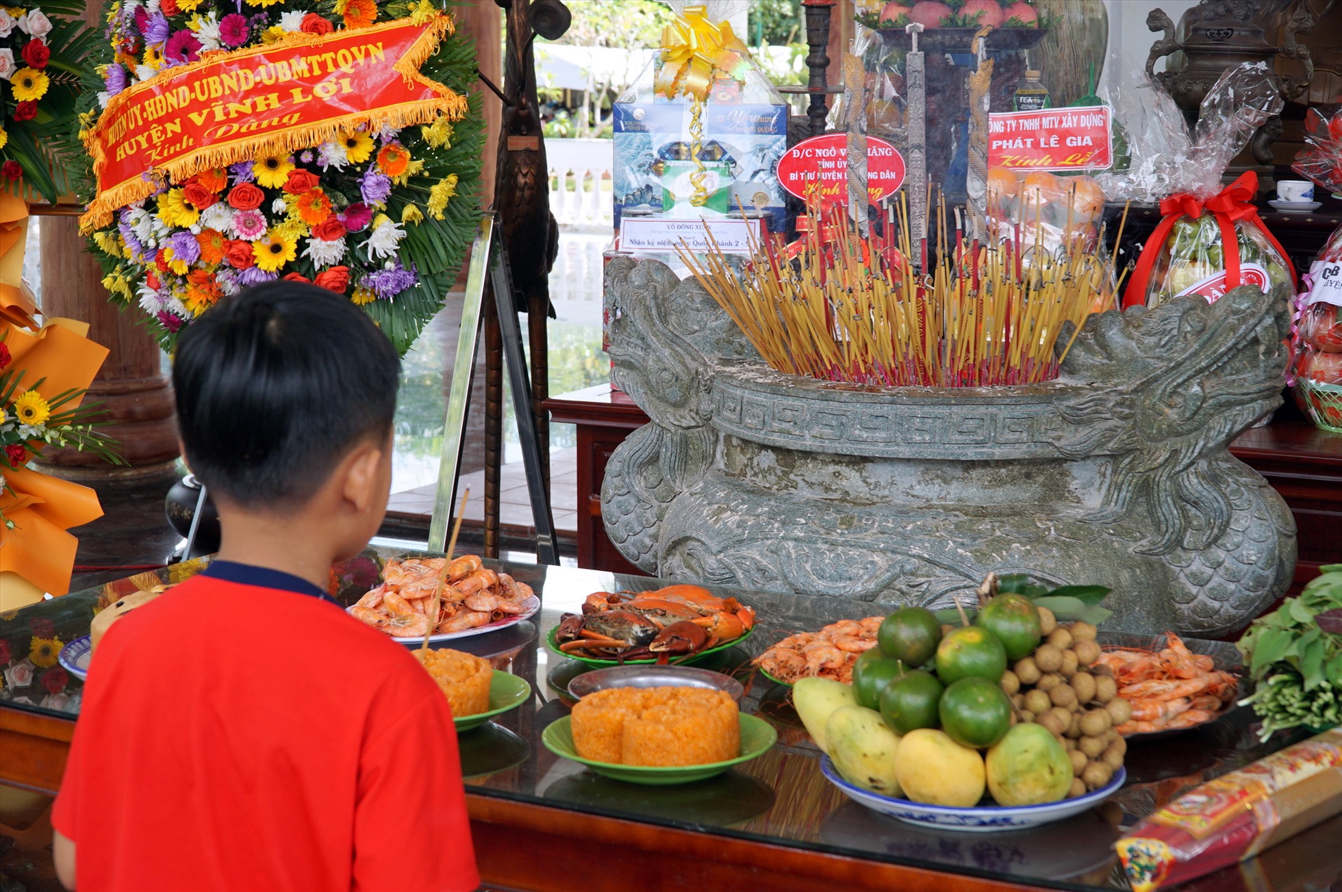 Một em thiếu nhi cùng gia đình đến thắp hương Bác Hồ.