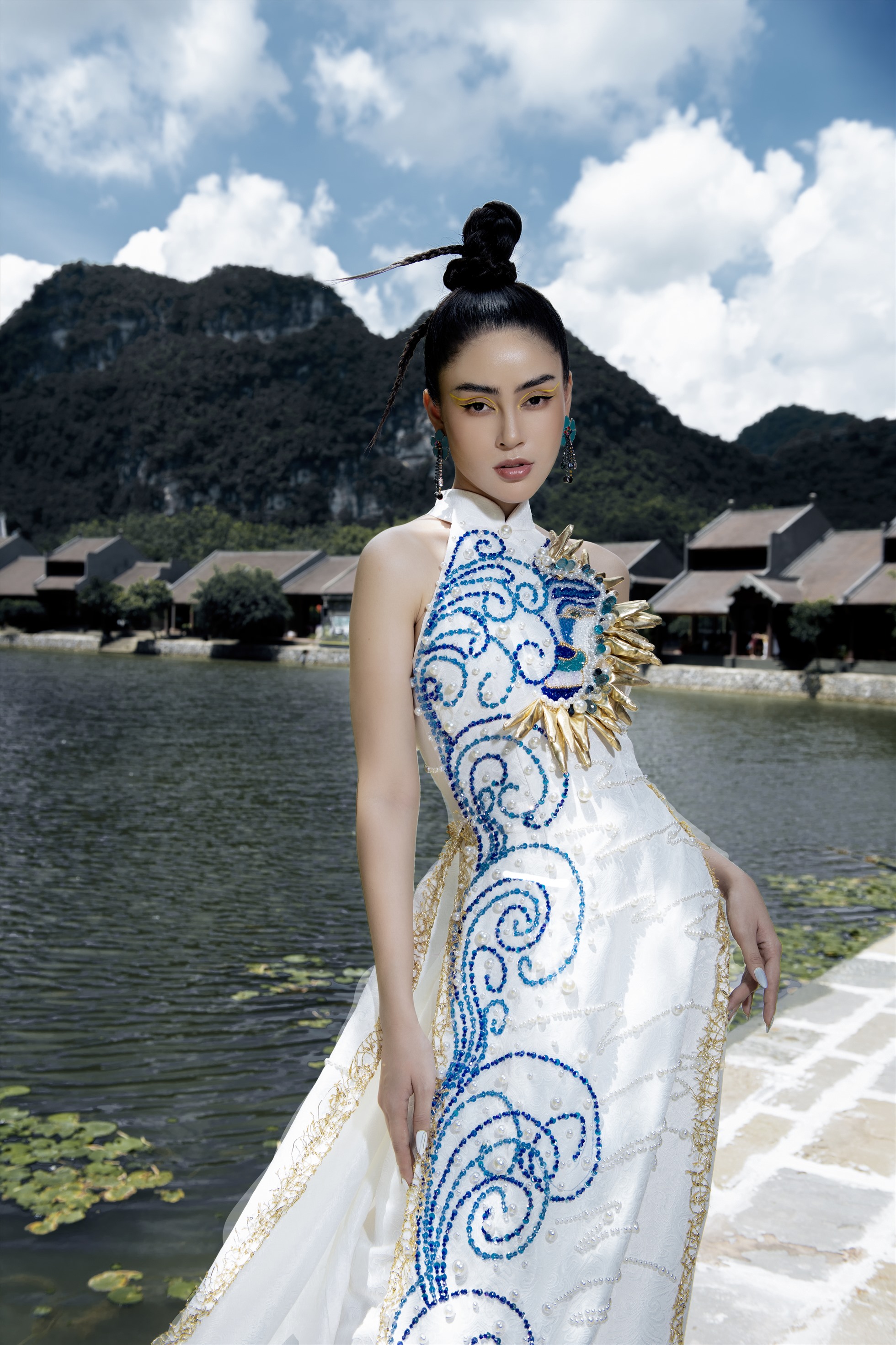 Áo dài khoét vai màu xanh được thiết kế trên nền vải gấm, đính kết hạt ngọc trai tạo nét quyền lực cho Lý Kim Thảo.
