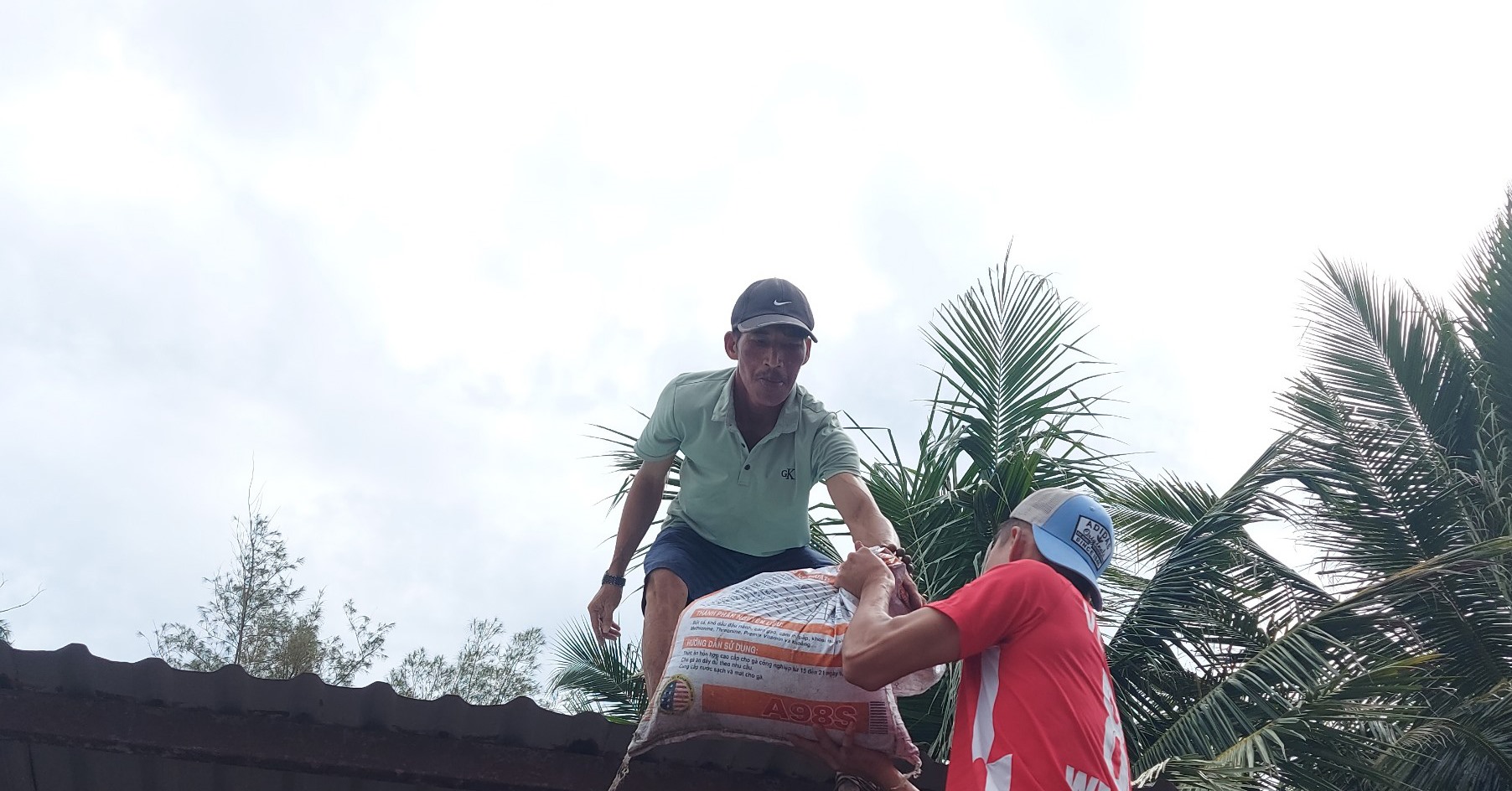 Người dân Quảng Nam đưa bao cát lên mái nhà, giữ mái nhà không bị tốc mái khi siêu bão Noru đổ bộ vào đất liền.