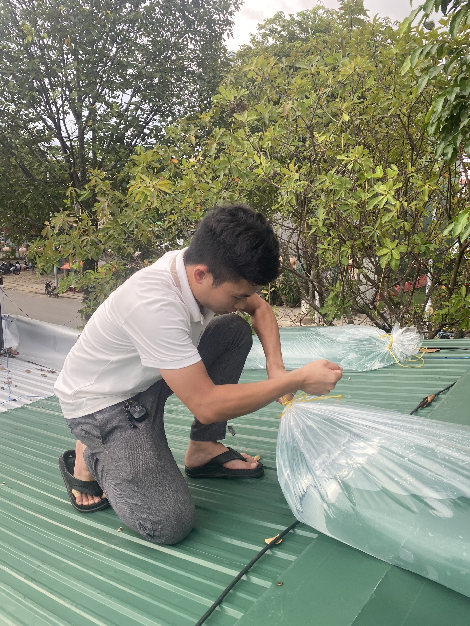 Anh Phạm Đình Hải ở phường Trương Quang Trọng, TP. Quảng Ngãi bơm nước vào bao để chằng phấn mái nhà.