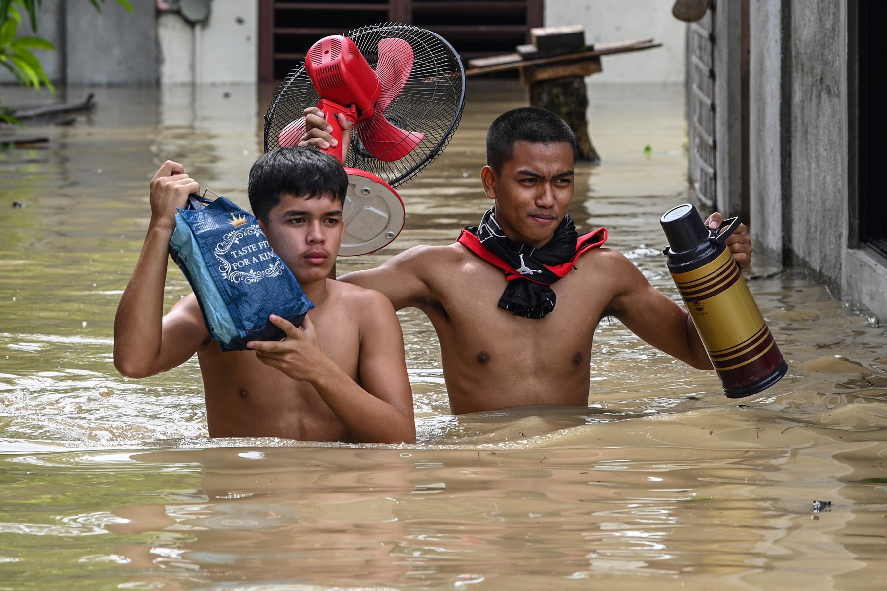Người dân mang theo đồ đạc sơ tán khỏi những ngôi nhà ngập nước sau siêu bão Noru ở San Ildefonso, tỉnh Bulacan, Philippines, ngày 26 tháng 9 năm 2022. Ảnh: AFP