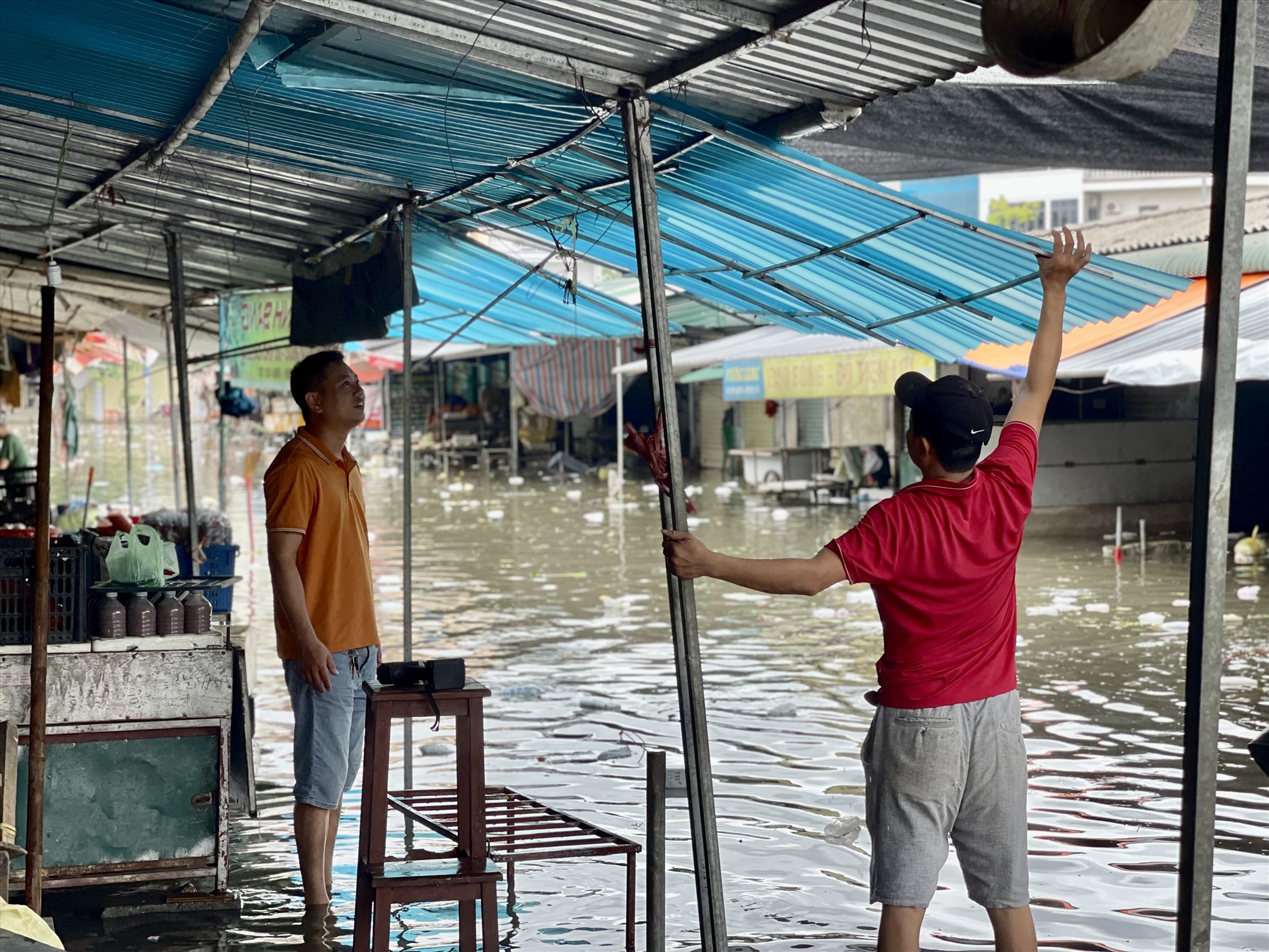 Tiểu thương sửa lại hàng quán sau ảnh hưởng của mưa lớn. Ảnh: Quỳnh Trang