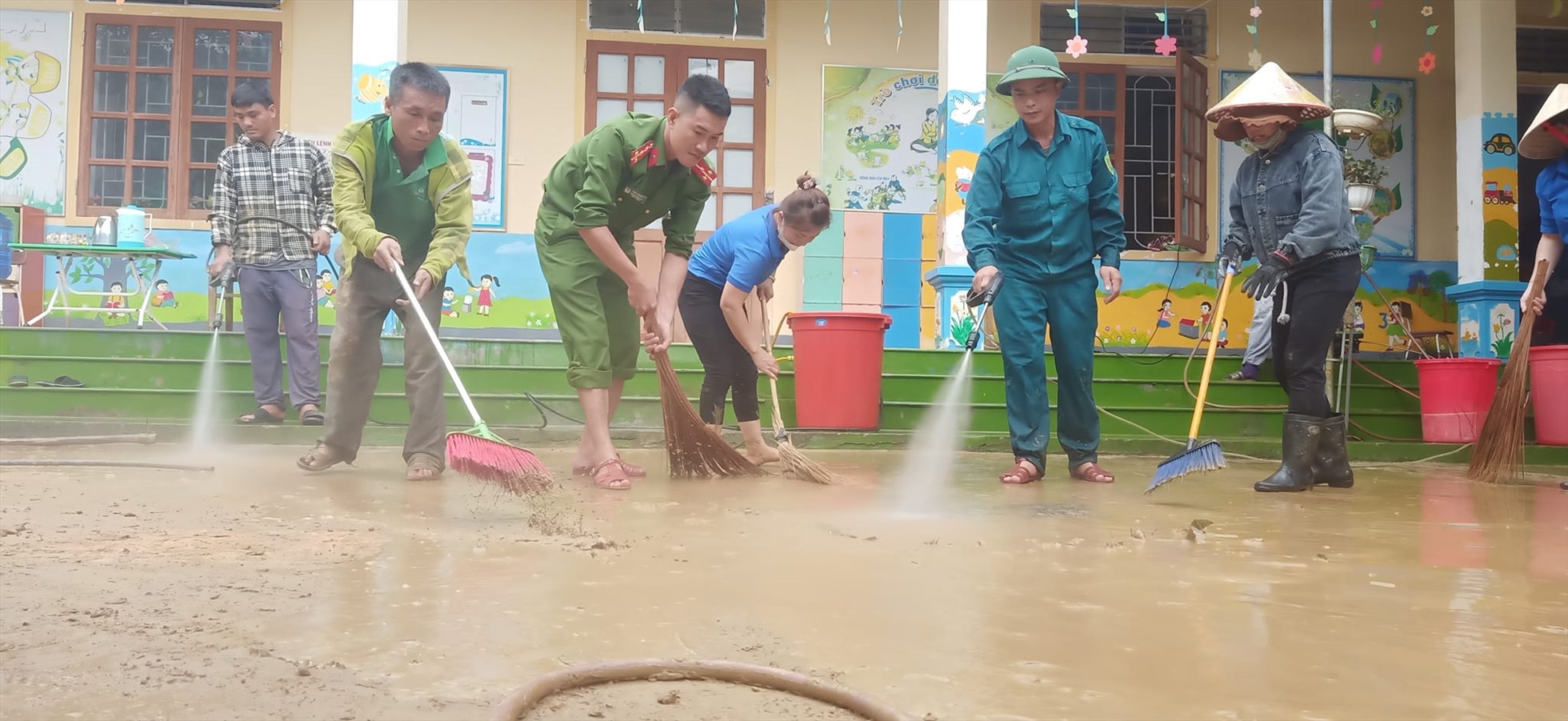 Các lực lượng chức năng và người dân địa phương hỗ trợ nhà trường khắc phục hậu quả mưa lũ. Ảnh: AN