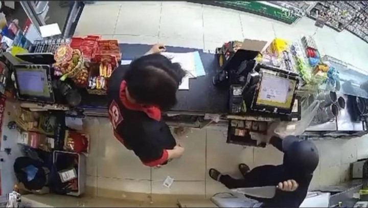 Hình ảnh tên cướp gí dao đe doạ nhân viên cửa hàng, chiếm đoạt tài sản. Ảnh: Công an
