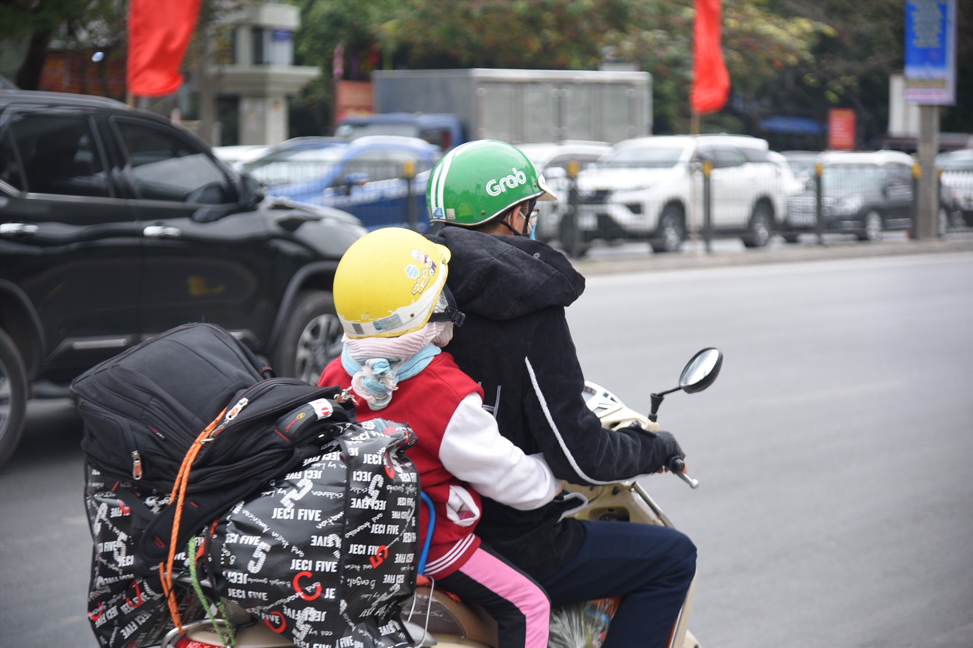 Một em nhỏ cùng phụ huynh đi xe máy về quê. Ảnh: Hữu Chánh