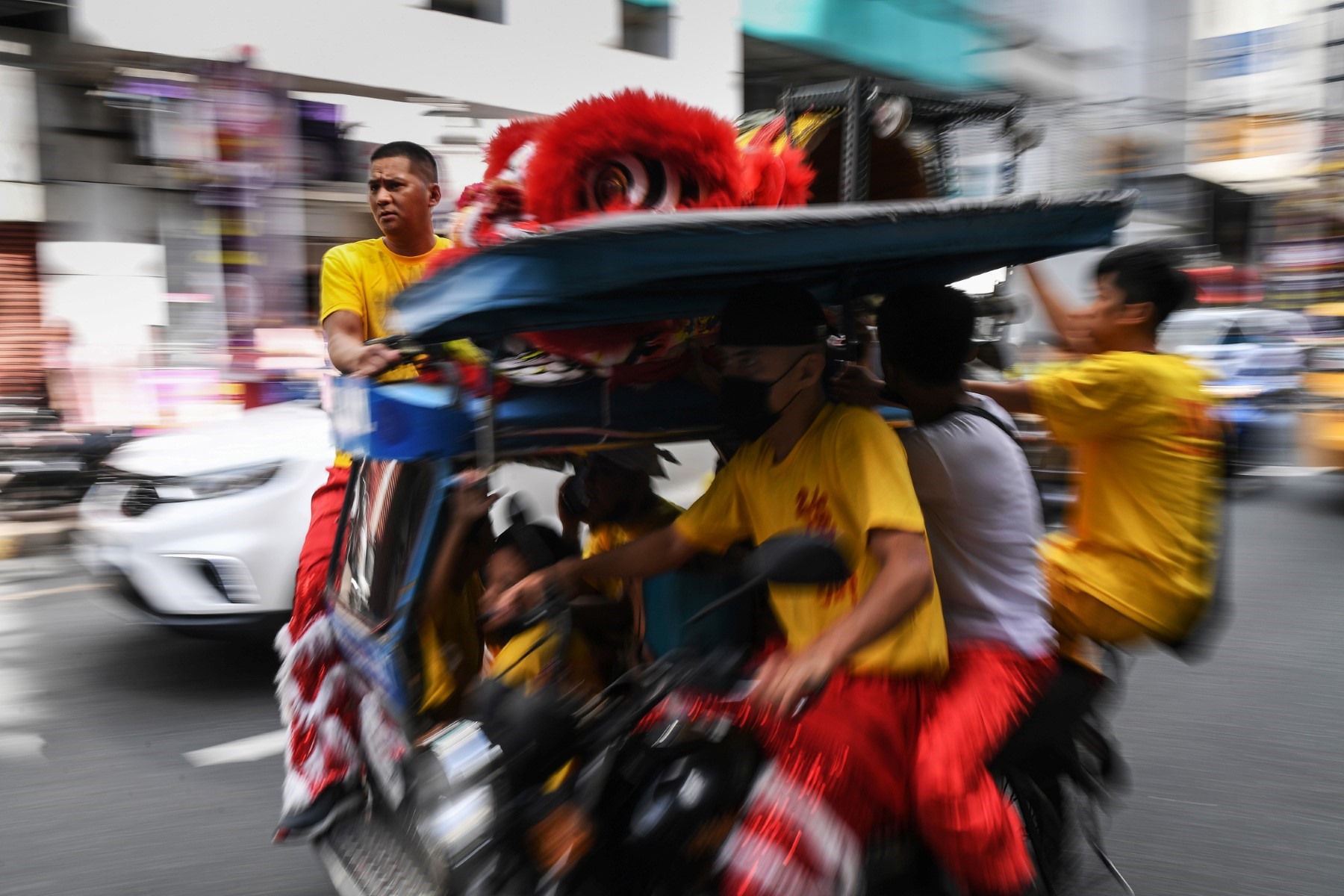 Đoàn múa lân đi xe ba bánh đến điểm biểu diễn ở khu Chinatown của Manila, Philippines. Ảnh: AFP