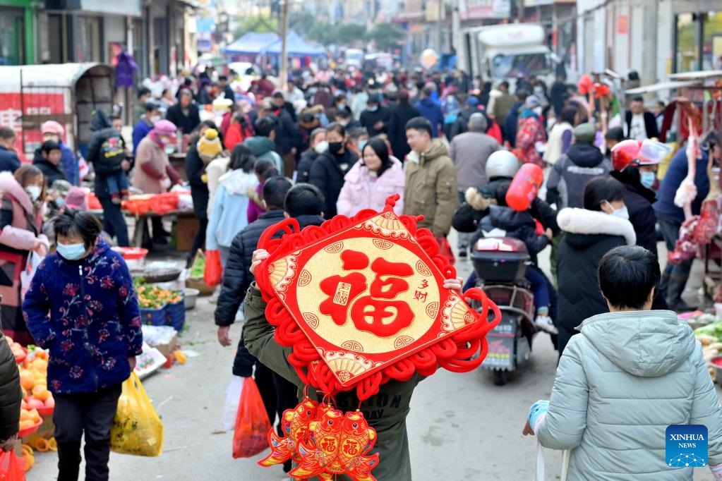 Một người dân mang đồ trang trí lễ hội trong một khu chợ ở thị trấn Jingzi, huyện Song Phong, tỉnh Hồ Nam, miền trung Trung Quốc. Ảnh: Tân Hoa Xã