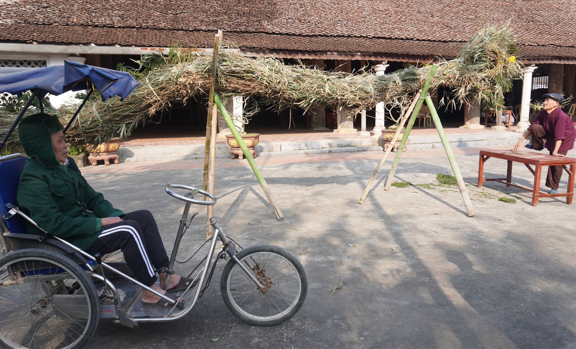 Dù đi lại khó khăn nhưng một cụ ông (ở thôn Đồng Bồng) vẫn ra đình làng xem công tác chuẩn bị cho đêm rước lửa cầu may. Ảnh: Quách Du