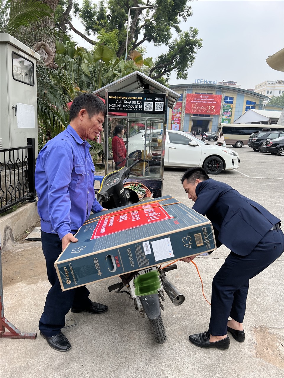 Anh công nhân (bên trái) nhờ người trọ giúp buộc chiếc Tivi trúng giải tại Tết Sum vầy do Liên đoàn Lao động Thành phố Hà Nội tổ chức. Ảnh: Linh Nguyên