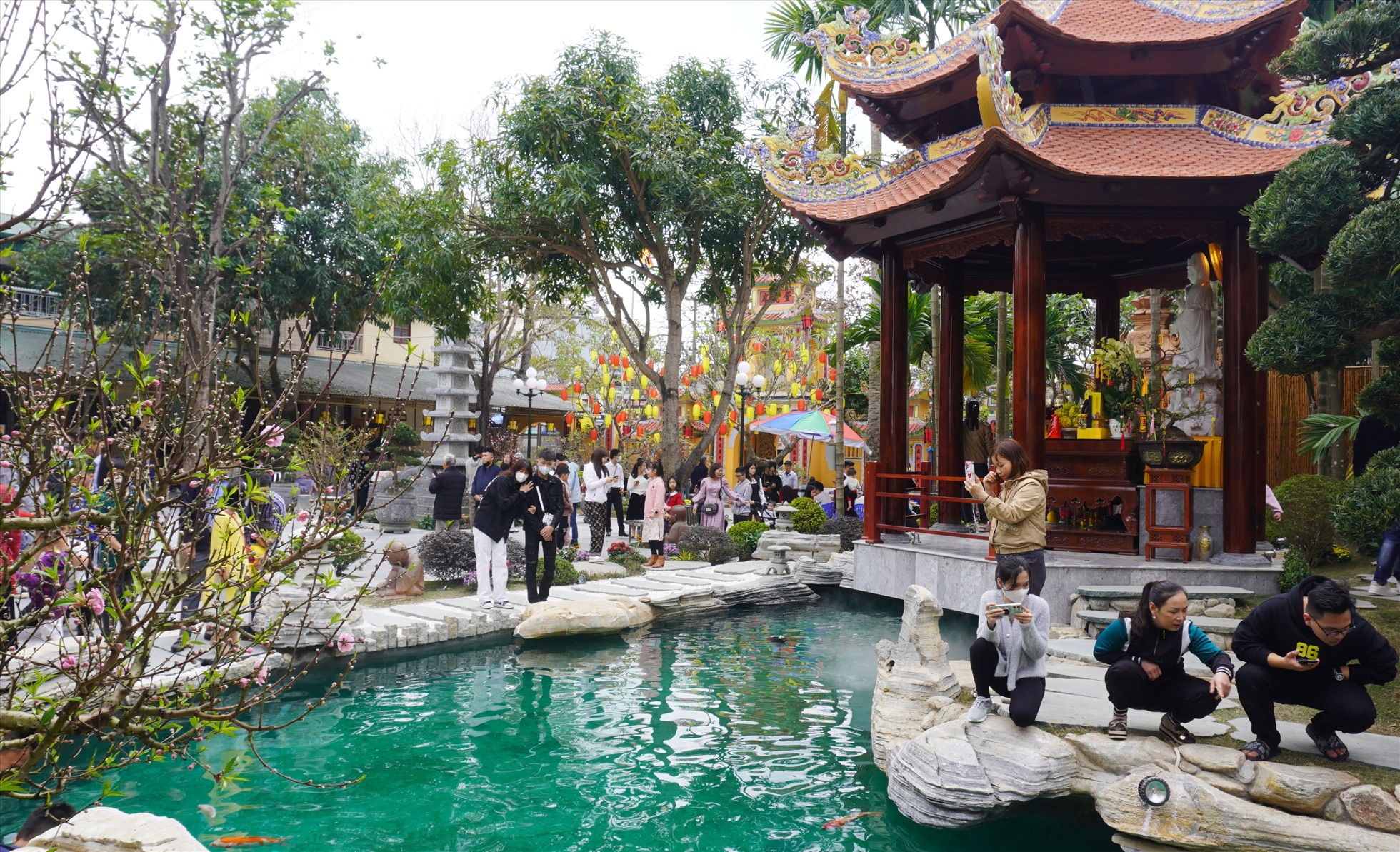 Du khách vãn cảnh xung quanh bể cá trong khuôn viên nhà chùa. Ảnh: Quách Du