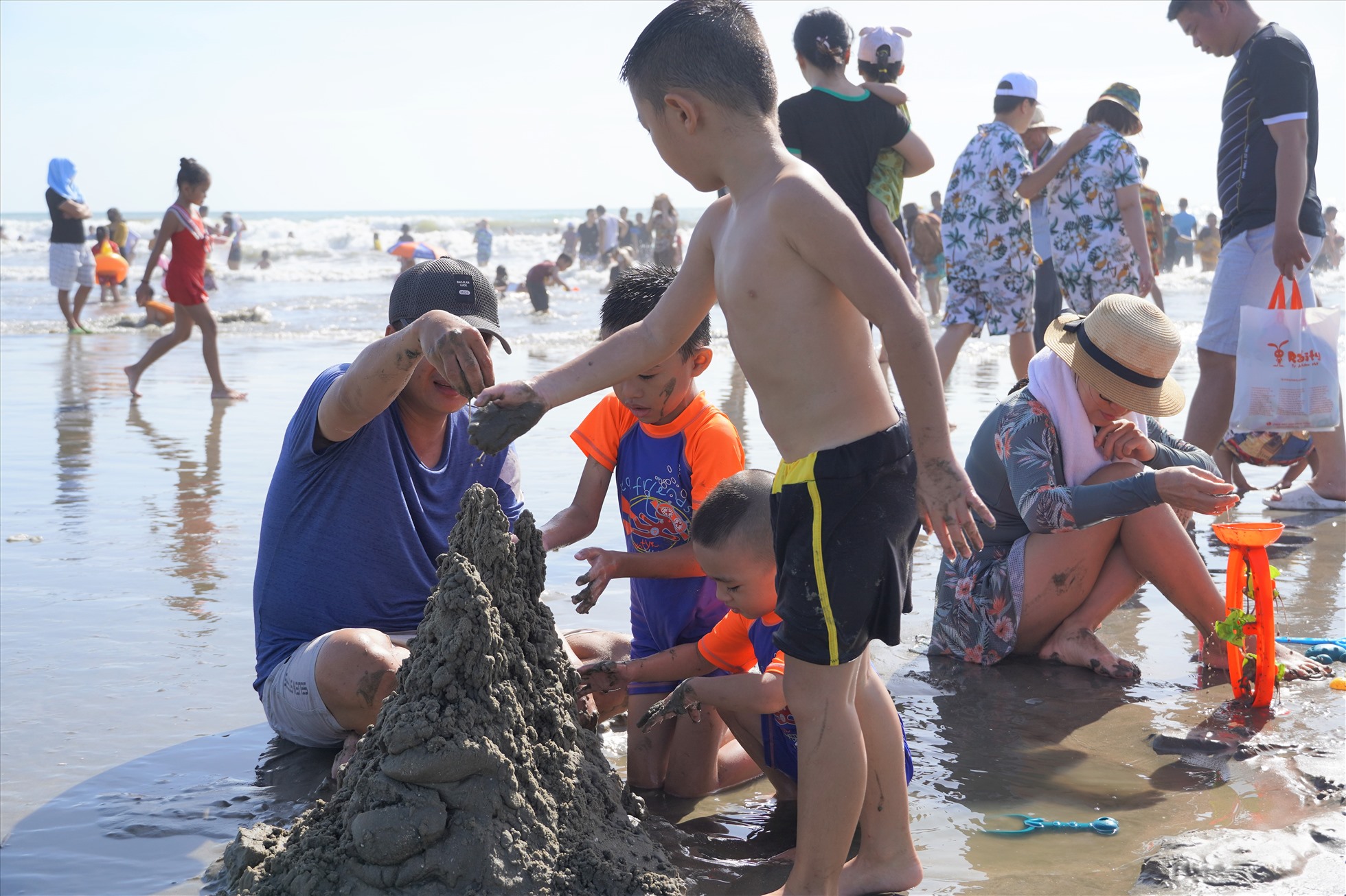 Nhiều gia đình lại chọn xây lâu đài cát gần mặt nước. Anh Phan Thanh Bình - du khách đến từ quận Bình Tân (TPHCM) cho biết, bãi cát rộng thế này thì tắm biển vui chơi thỏa thích hơn so với chiều mùng 2 khá chật chội, nên từ sáng sớm gia đình đã dẫn các cháu ra biển vui chơi. Ảnh: Thành An
