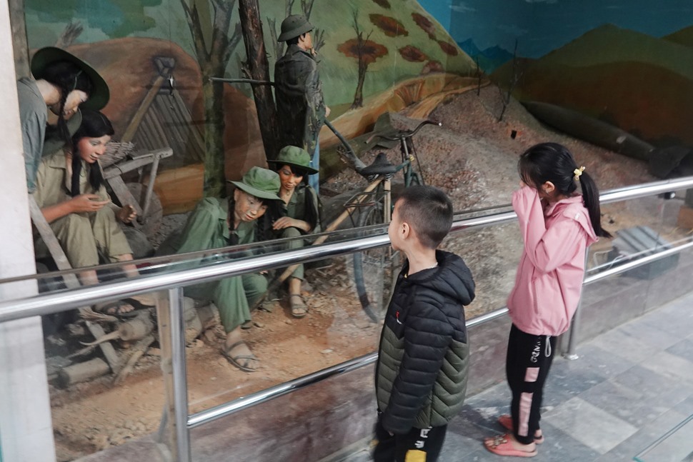 Trẻ em tò mò bên những bức tượng tái hiện cảnh thực hiện nhiệm vụ của thanh niên xung phong Ngã ba Đồng Lộc thời chiến tranh. Ảnh: Trần Tuấn.