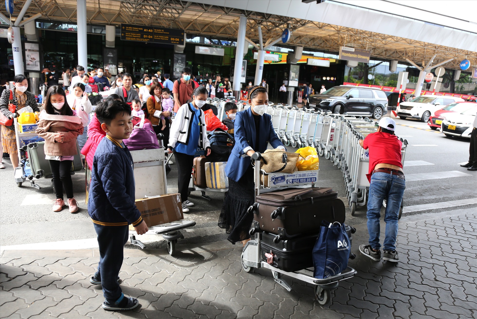 Nhiều hành khách lỉnh kỉnh hành lý, hối hả rời nhà ga đến khu vực đón xe sau khi các chuyến bay hạ cánh.