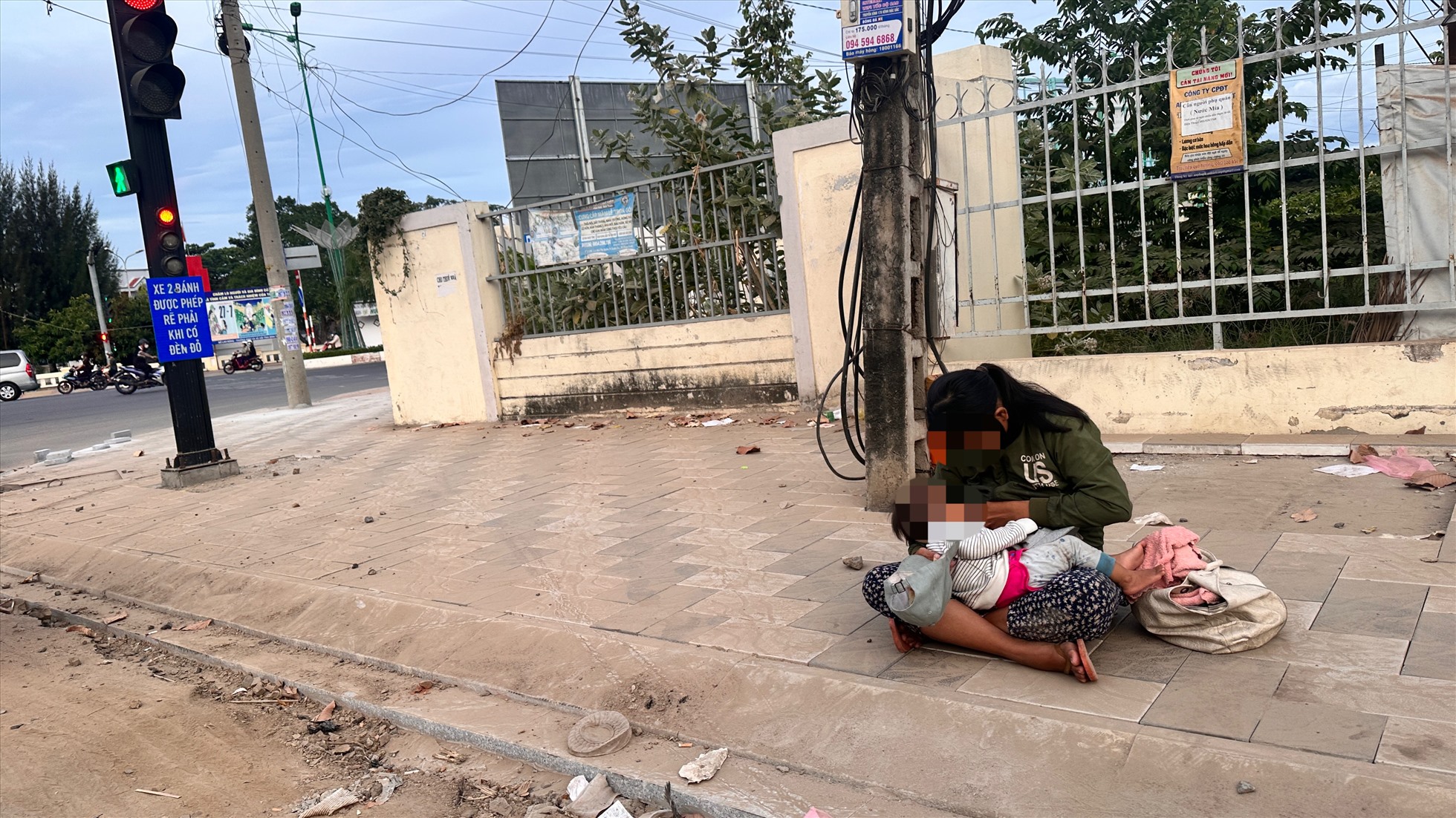 Người phụ nữ ôm một trẻ nhỏ ngồi ăn xin ở chốt đèn tín hiệu ngã tư đại lộ Lê Duẩn-Nguyễn Hội, TP.Phan Thiết. Ảnh: Duy Tuấn