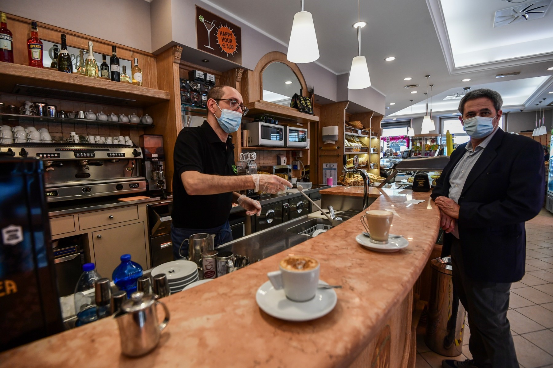Nhân viên pha chế đang phục vụ khách tại quán cà phê Buttarelli ở Milan, ngày 18.5. Ảnh: AFP