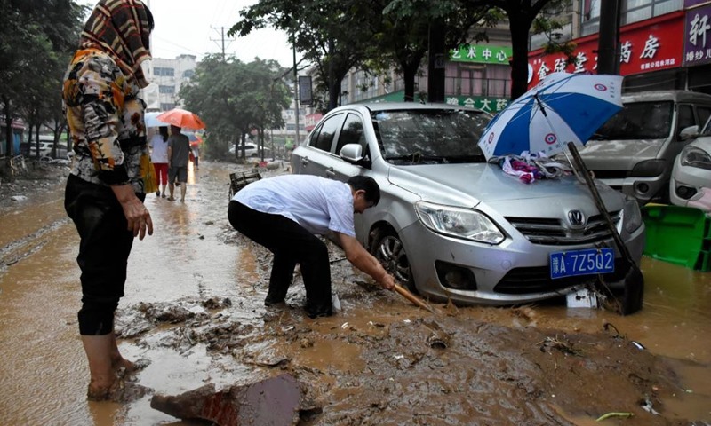 Người dân dọn dẹp bùn đất quanh một chiếc ô tô bị mắc kẹt ở thành phố Củng Nghĩa, Trịnh Châu, tỉnh Hà Nam của Trung Quốc tháng 7.2021. Đây là một trong những địa điểm chịu thiệt hại nặng nề do trận mưa lớn vào ngày 20.7.2021. Ảnh: Xinhua