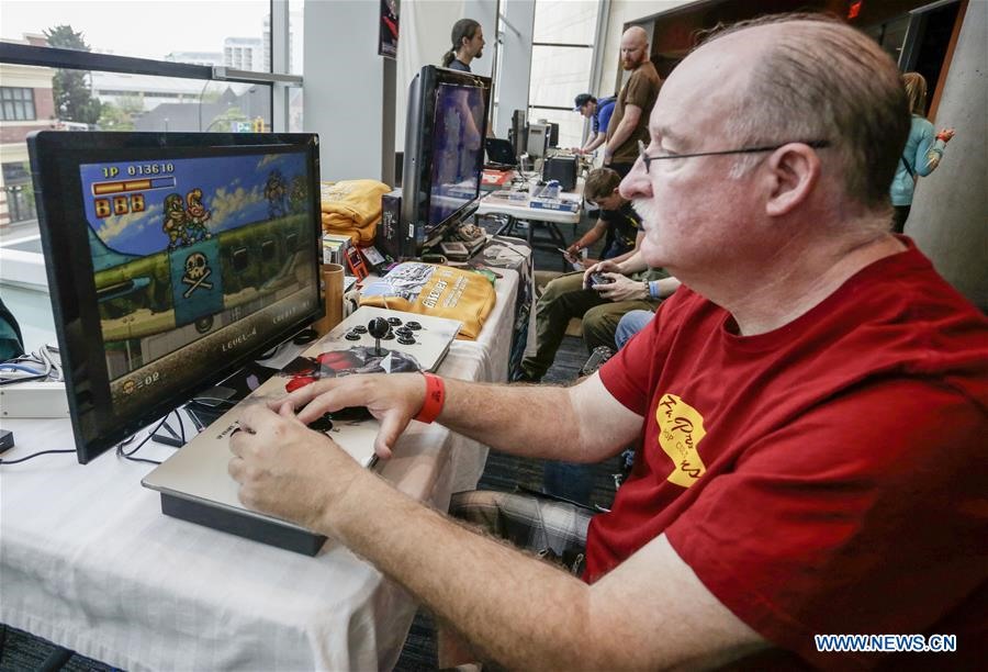 Một du khách chơi thử trò chơi trên máy tính tại Vancouver Retro Gaming Expo ở New Westminster, Canada, ngày 22.6.2019. Ảnh: Xinhua