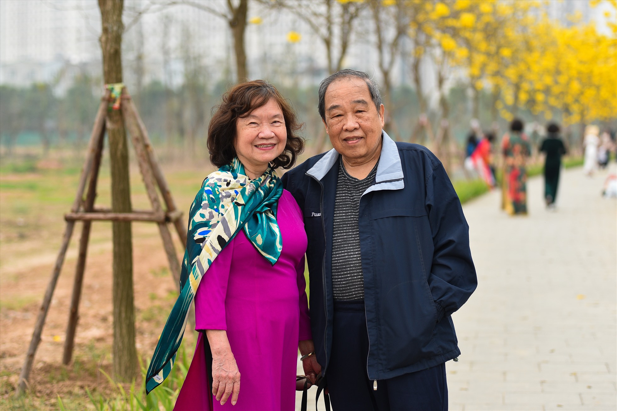 Ông Trần Trung Tín cùng vợ mình lưu giữ khoảnh khắc “hồi xuân” bên hàng cây hoa Phong Linh. Ảnh: PHƯƠNG NAM
