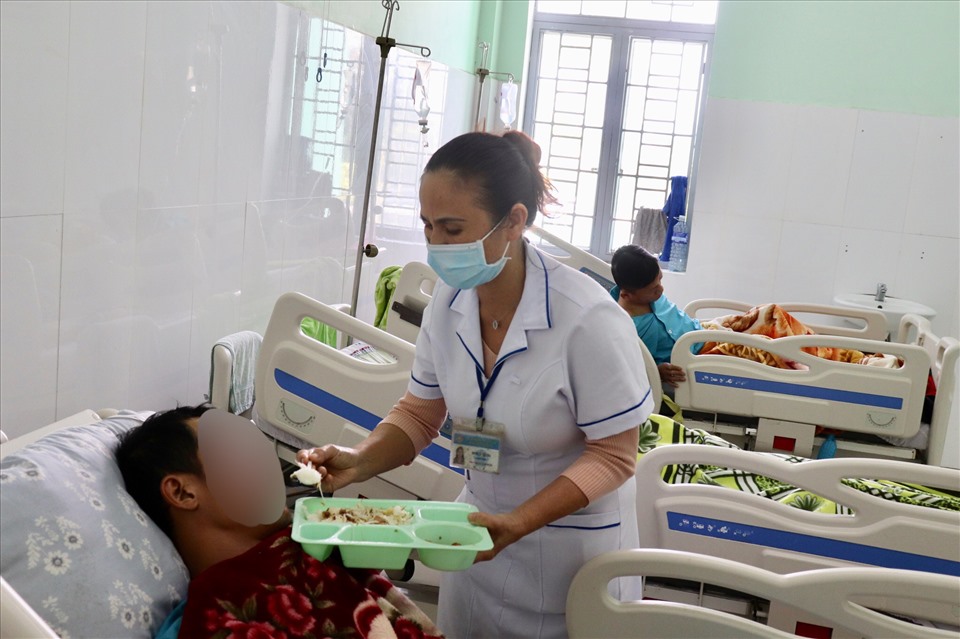 Bà Lê Thị Tha tận tay bón cơm cho bệnh nhân không ăn được. Ảnh: Nguyễn Linh