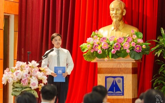 Nguyễn Hải Đăng đứng trước lá cờ Tổ quốc, cờ Đảng, chân dung Chủ tịch Hồ Chí Minh đọc lời tuyên thệ.