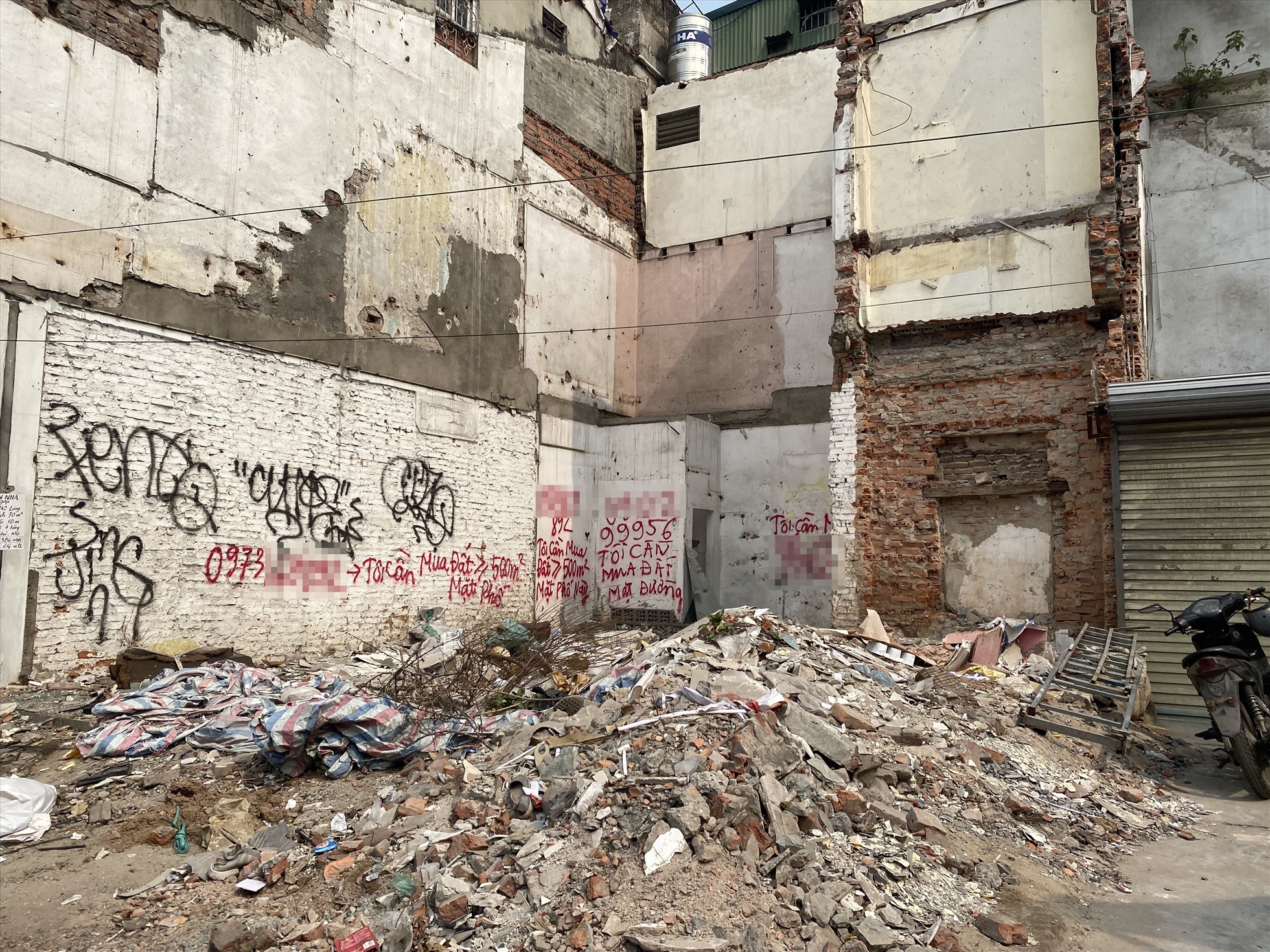 Trên tường của một số ngôi nhà vừa bị phá dỡ này xuất hiện dòng chữ “cần mua đất mặt phố này“. Ảnh: Vĩnh Hoàng