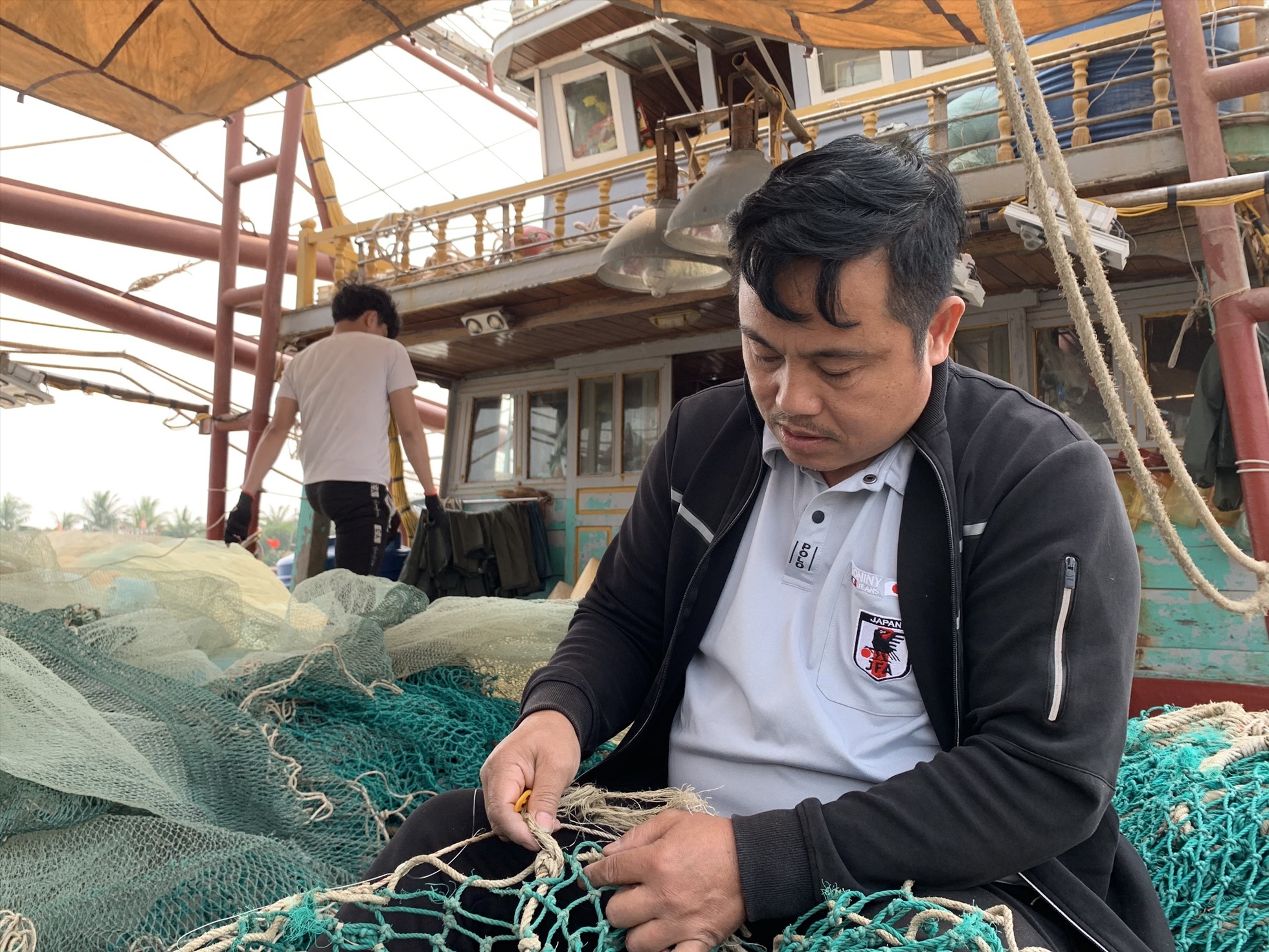 Anh Nguyễn Đức Văn vá lưới chuẩn bị ra khơi. Ảnh: Lương Hà