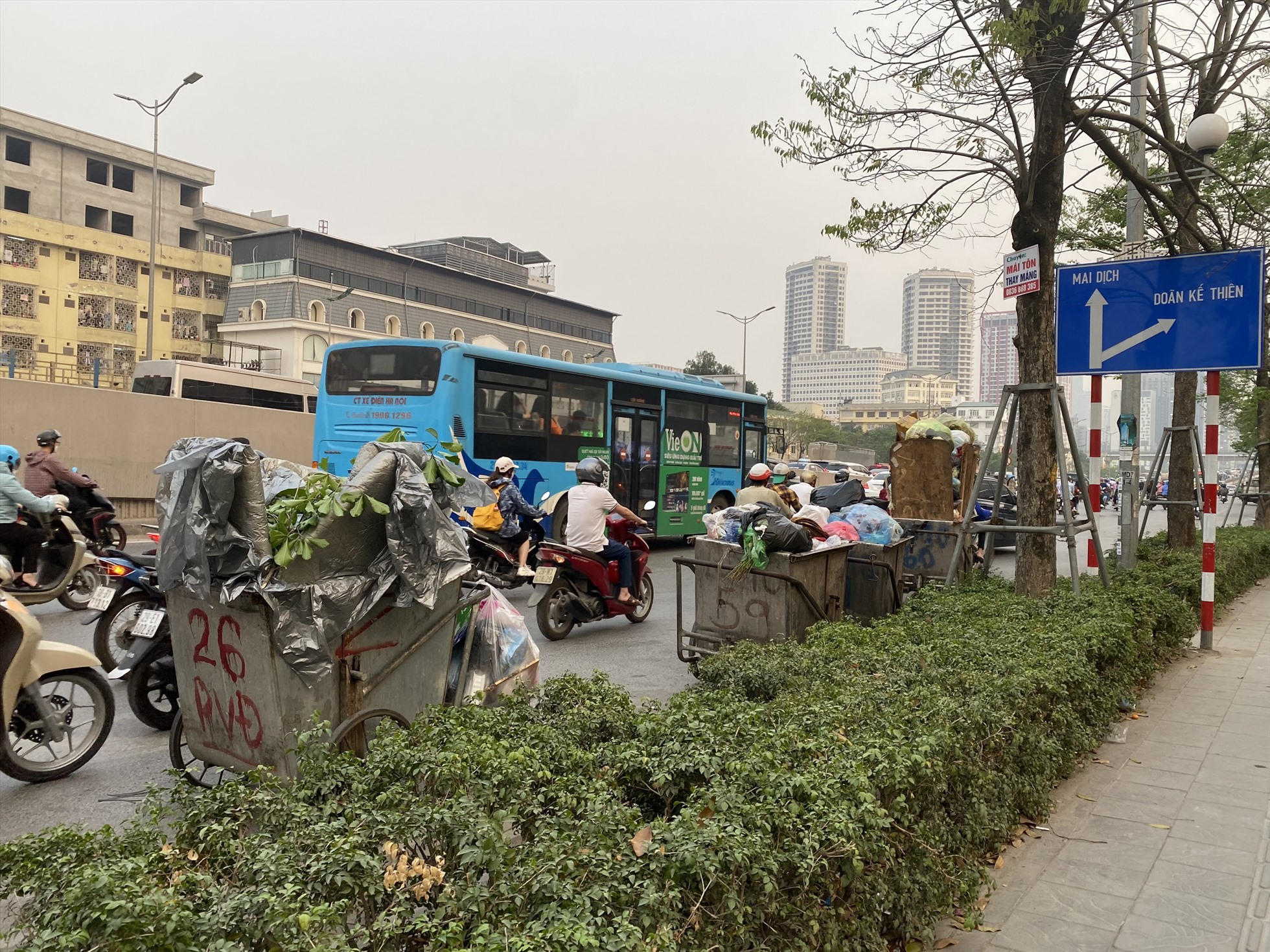 Những xe rác đầy ắp để dọc đường Phạm Văn Đồng (quận Cầu Giấy) gây nguy hiểm cho người tham gia giao thông. Ảnh: Phương Trang