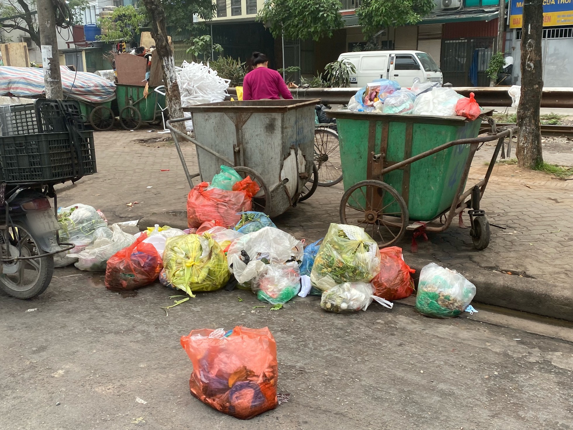 Tại đường Giải Phóng (quận Hoàng Mai), người dân thản nhiên vứt rác xuống lòng đường mặc dù có xe rác bên cạnh. Ảnh: Phương Trang