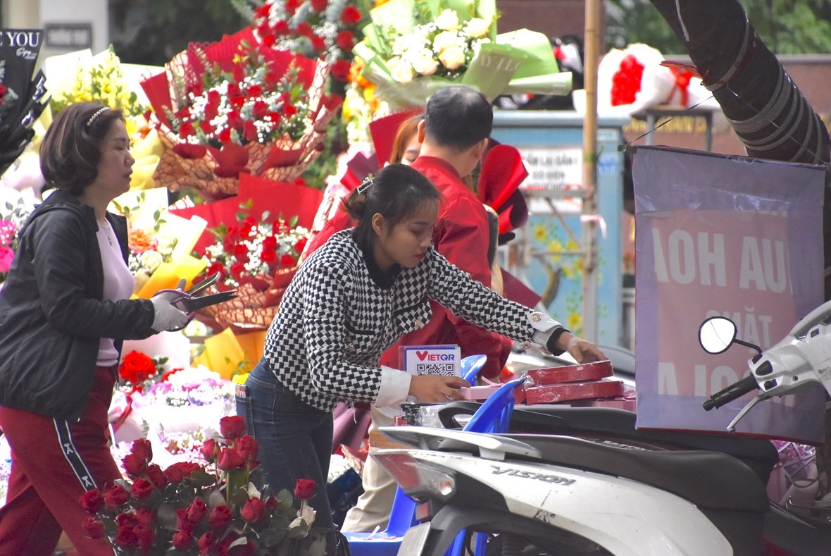 Chị Thu Hà - Chủ một tiệm hoa trên đường Nguyễn Phong Sắc nhanh tay thanh toán cho khách hàng. Ảnh: Lương Hạnh.